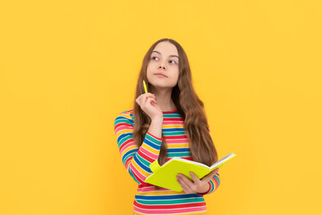 Thoughtful kid think over school essay holding pen and copybook yellow background, story - obrazy, fototapety, plakaty