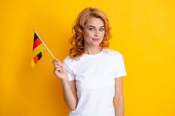 Portrait of positive student woman holding German flag. Isolated on yellow background. Happy girl...