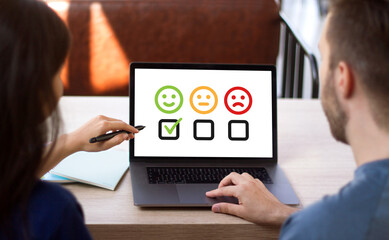 Customer experience concept, man and woman checking box of excellent smiley face rating for a satisfaction survey on computer laptop.