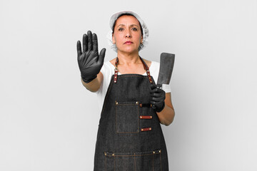 middle age woman looking serious showing open palm making stop gesture. butcher concept