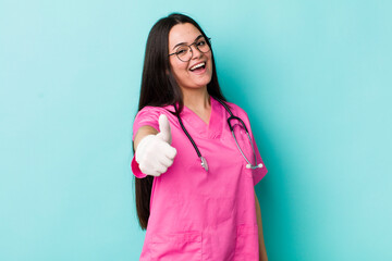 young adult woman feeling proud,smiling positively with thumbs up. veterinarian concept