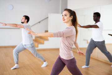 Fototapeta na wymiar Woman and men dancing in fitness studio. Aerobic dance group practice.