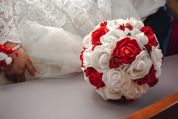Beautiful bridal bouquet with white and peach roses, red peonies, and other flowers on a white table. Close-up, indoor.