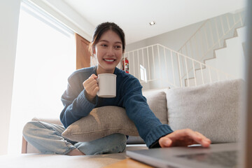 Portrait of Young Asian woman using social media by laptop. Lifestyle ,Shopping online, relax on sofa.