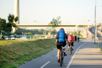 Sportive couple cycling by Ada Bridge over the Sava river in Belgrade, Serbia, on hot summer day....