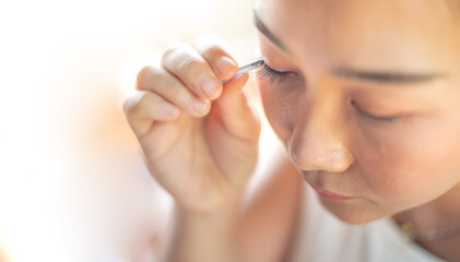 Female hand holding the eyelash and preparing to attach to her eye.