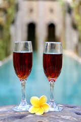 glasses with red wine near the swimming pool in the tropics