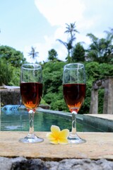 glasses with red wine near the swimming pool in the tropics