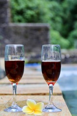 glasses with red wine near the swimming pool in the tropics