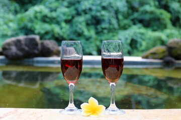 glasses with red wine near the swimming pool in the tropics