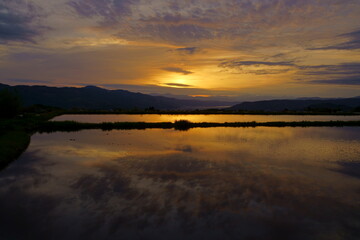 Obraz premium 田植え前の水田の水に映り込む山里の夕景