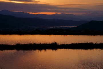Fototapeta premium 田植え前の水田の水に映り込む山里の夕景