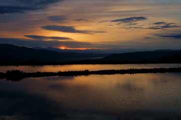 田植え前の水田の水に映り込む山里の夕景