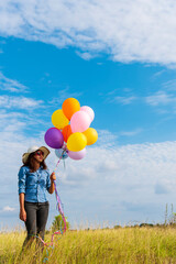 Woman holding balloons running on green meadow white cloud and blue sky with happiness Cheerful and relax. Hands holding vibrant air balloons play on birthday party happy times summer sunlight outdoor