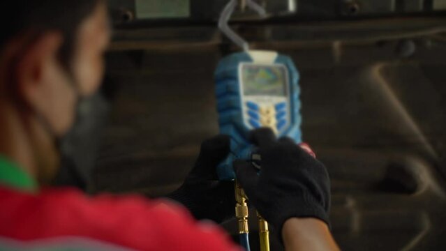 A technician is checking car air conditioner check service, leak detection, fill refrigerant.Device and meter liquid cooling in the car by specialist technicians.