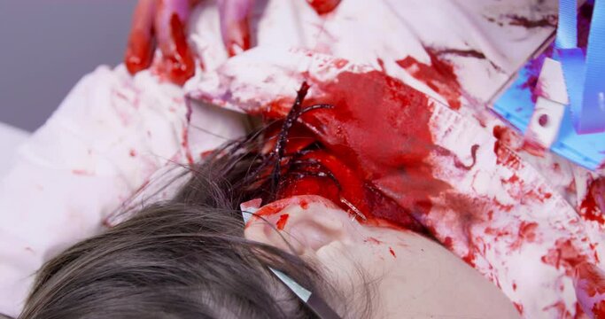 Creepy hungry male zombie with bloody face attacked young woman, and now he is biting off pieces of meat from her neck, close up. Halloween themed zombie apocalypse party