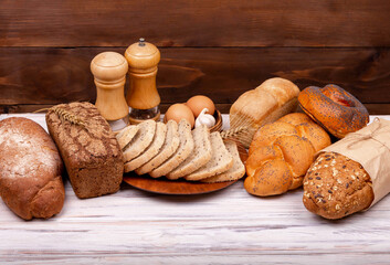 Concept of homemade bread, natural farm products, domestic production. Healthy and tasty organic food. Assortment of baked bread on dark and white background. Empty space for text.