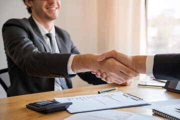 Businessmen shake hands after meetings and negotiate business deals. The entrepreneur smiles and is happy with the contract agreement and the joint venture share.