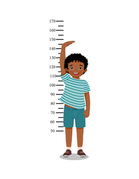 Cute Little African boy measuring height of his growth on the background of wall 