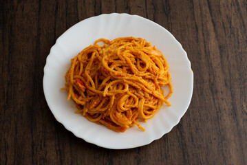 Spaghetti dish served in white plate on wooden table.