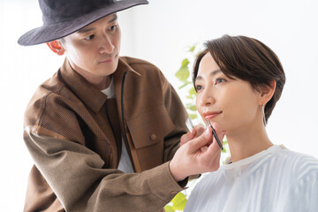 美容院で男性美容師でメイクを受ける日本人女性 - obrazy, fototapety, plakaty
