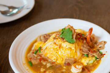 Spicy scrambled eggs with pork and shrimp, ready to eat, laid out on a white plate.