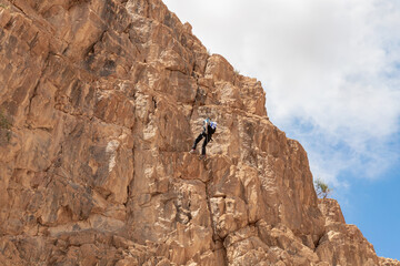Experienced athlete on Israel Independence Day descending with equipment for rappel in mountains of Judean Desert, near Khatsatson stream, near Jerusalem, Israel.