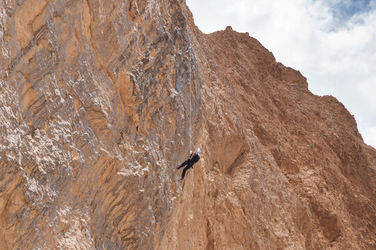 Experienced athlete on Israel Independence Day descending with equipment for rappel in mountains of Judean Desert, near Khatsatson stream, near Jerusalem, Israel.