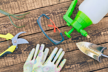 Pruner, rake, pressure sprayer, garden gloves, shovel and protective glasses on boards