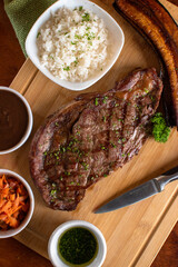 Angus beef grill with 3 sides and rice sauce wood table with a knife
