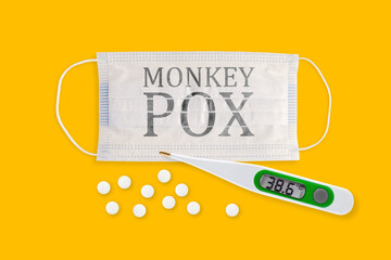 Face masks with inscriptions MONKEY POX. Monkey pox outbreak around the world. Face masks, thermometer and pills isolated on a yellow background.