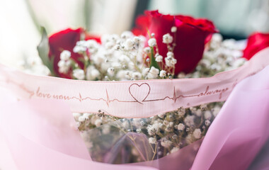 bouquet of white flowers and red roses, pink ribbon with heart