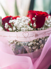 bouquet of red roses with pink ribbon