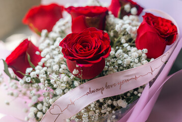 bouquet of red roses with a ribbon writing 