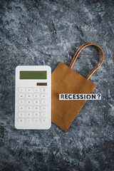 recession text over shopping bag next to calculator