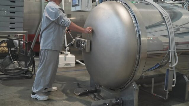 Male workers load a horizontal type autoclave in a food production. autoclave sterilization unit