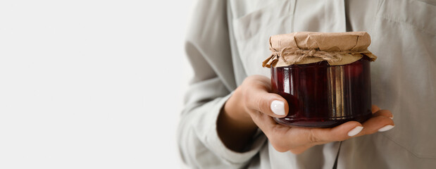 Woman holding glass jar of sweet jam on white background with space for text, closeup - Powered by Adobe