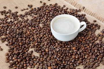 Brewed coffee in a cup against the background of coffee beans