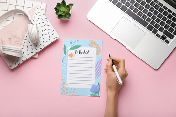 Female hand with laptop, to-do list, notebook and headphones on color background