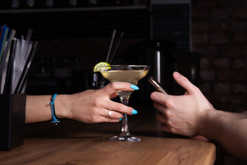 Bartender treats customer to margarita cocktail. Close-up.