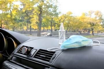 Fototapeta na wymiar Bottle of sanitizer and medical mask in car