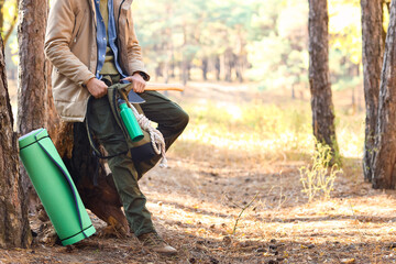 Male tourist with backpack and survival kit in forest