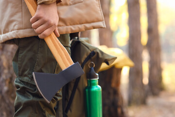 Male tourist with axe in forest, closeup