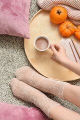 Woman drinking tasty pumpkin coffee on floor in room
