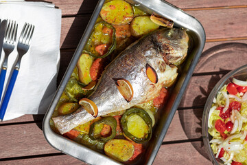 Delicious baked whole fish with herbs and lemon in a metal baking tray. selective focus. close up.
