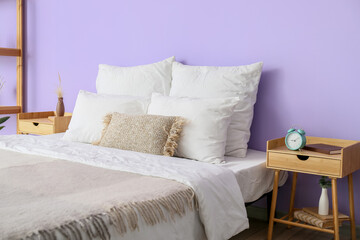 Comfortable bed with soft pillows near color wall