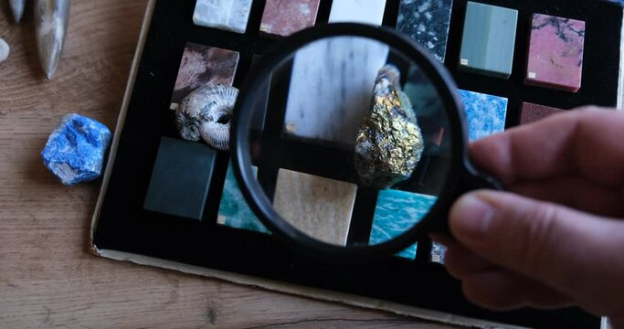Chalcopyrite mineral or copper pyrite also copper ore. Scientist examining chalcopyrite through magnifying glass