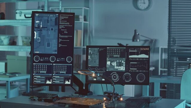 No people slowmo of workplace of electronics engineer with printed circuit boards and two computer monitors with data on desk in dark laboratory