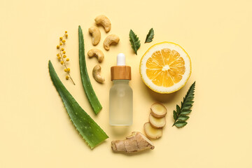 Fototapeta na wymiar Bottle of natural serum, plant leaves, flowers, cashew nuts, lemon and ginger on beige background