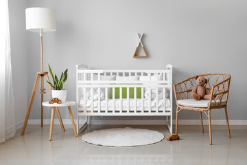 Interior of light nursery with baby crib, lamp, table and armchair - obrazy, fototapety, plakaty